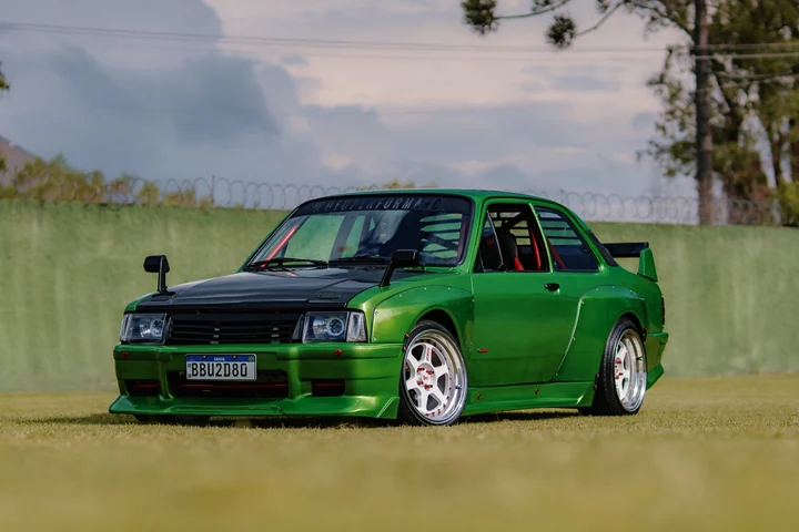 Green Chevette with a black hood, wide fenders and white wheels.